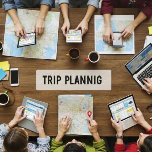 Group of travelers collaborating on trip planning tools with devices and maps